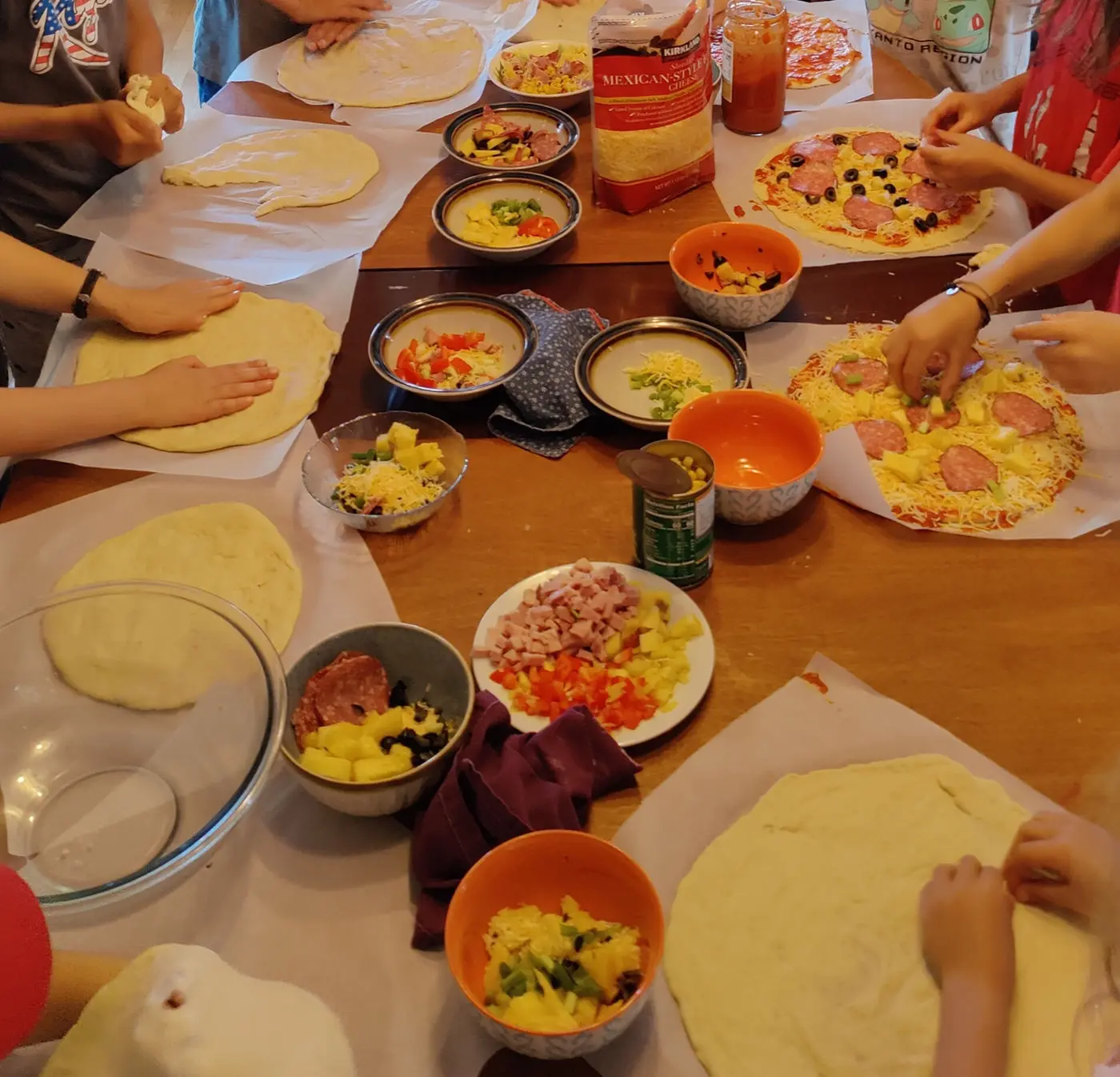 Kids topping their own homemade pizzas at cooking camp