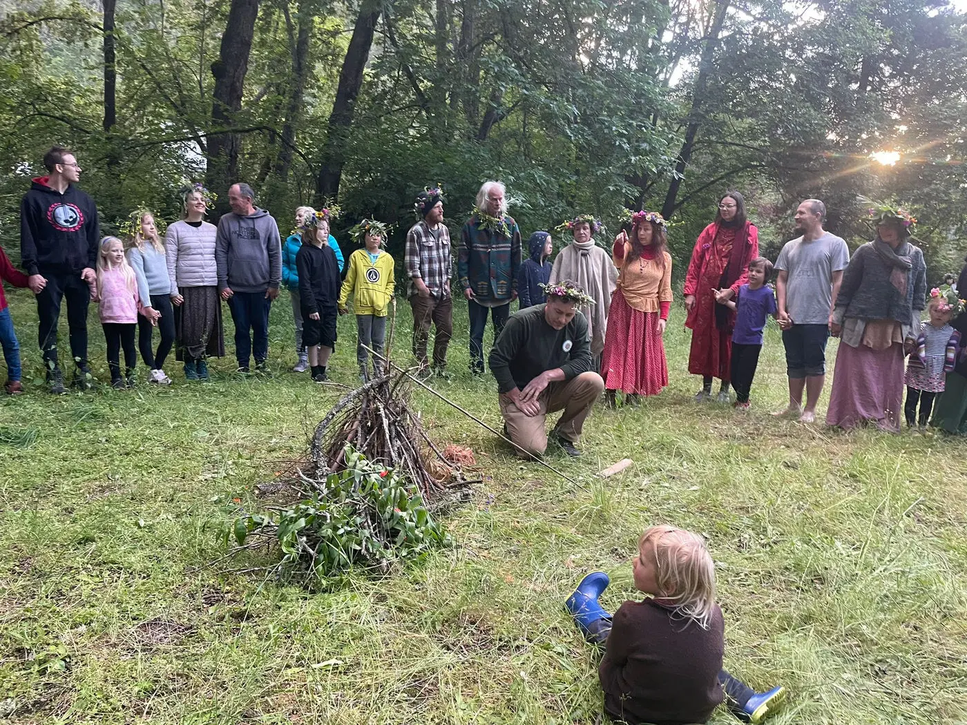 Families in a circle watching a fire being started by hand