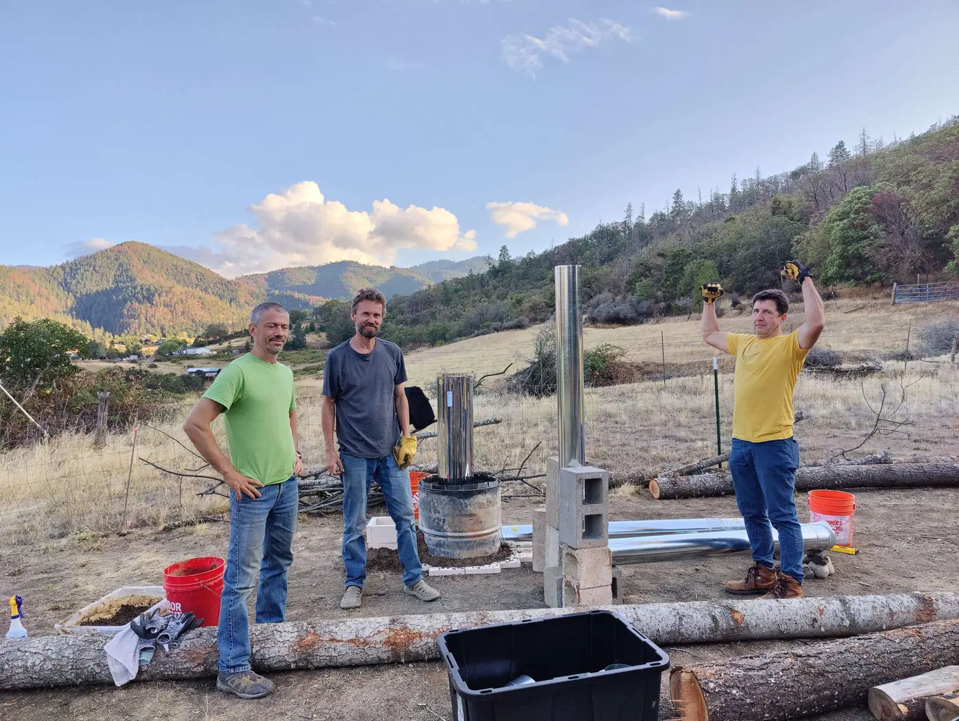 Friends cheering beside the finished rocket mass heater outdoors